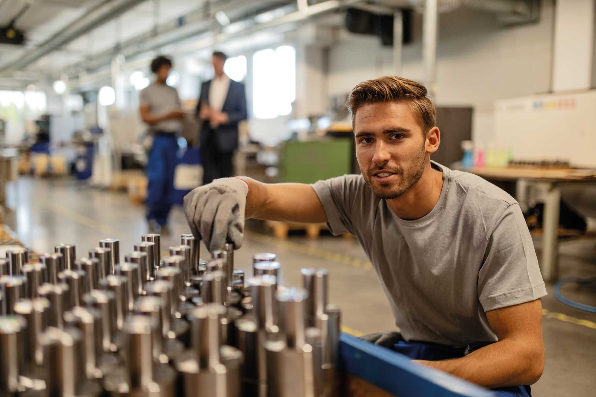 young-happy-manual-worker-analzying-quality-steel-rods-while-working-industrial-building-ad-looking-camera